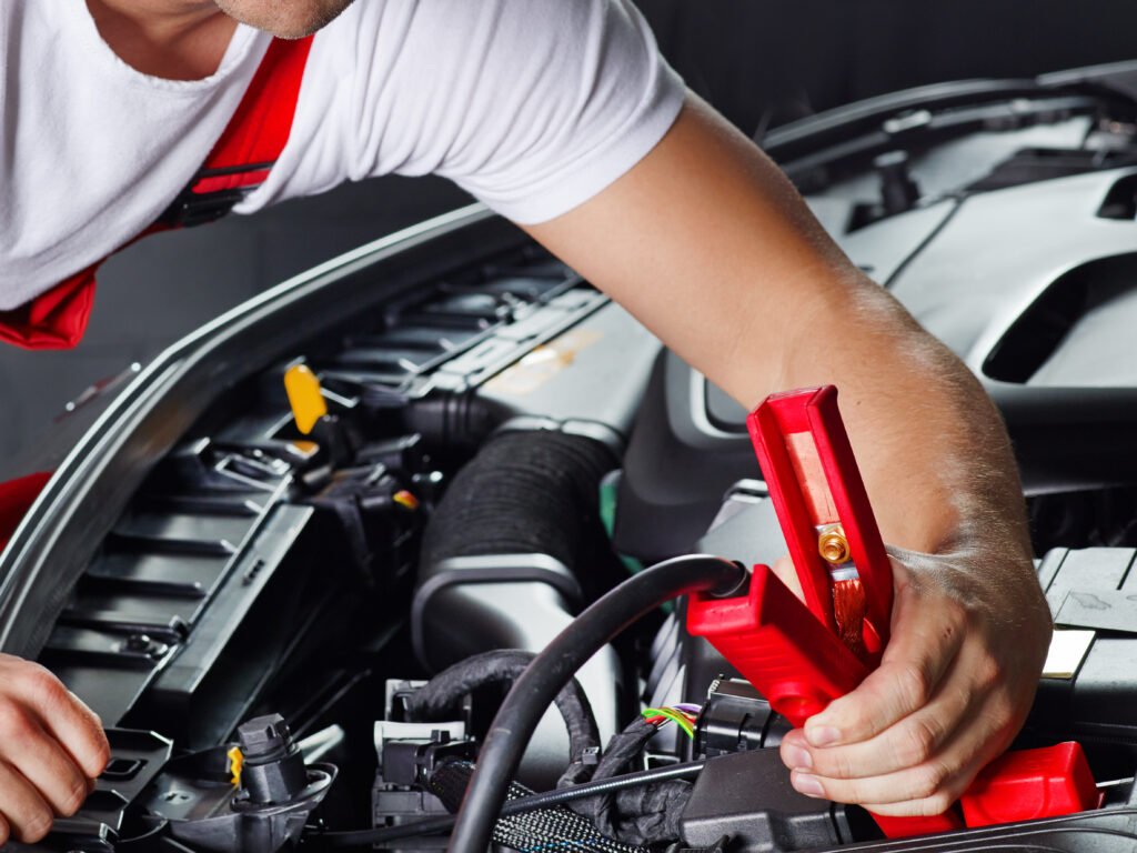 Gros plan sur des câbles de démarrage rouges et noirs branchés sur les bornes d'une batterie automobile